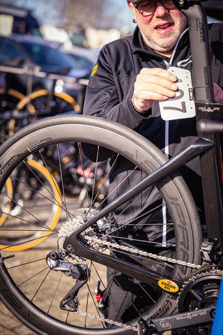 A man with a number 17 race bib is standing in front of bicycles.