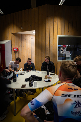 A group of cyclists gathered around a table at the Wielrennen Ster Van Zwolle race.