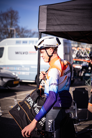 A man is wearing an orange and white jersey for a cycling event.