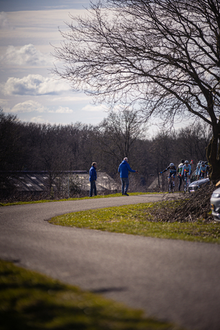 A group of cyclists on a road with a man in the foreground.