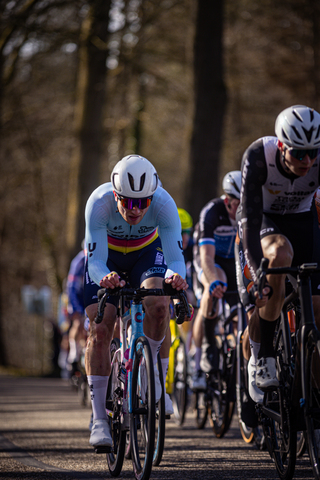 A group of cyclists on a street, one of which is wearing the number 1.