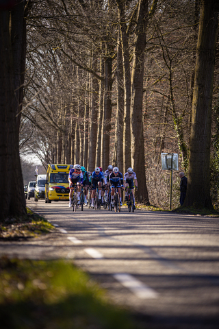 A group of bicycle riders with the numbers 1 to 8 riding down a road.