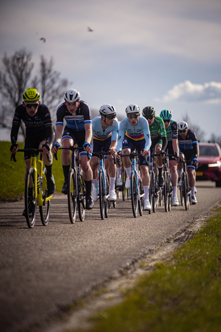 Several cyclists wearing blue and white jerseys are riding on a road.