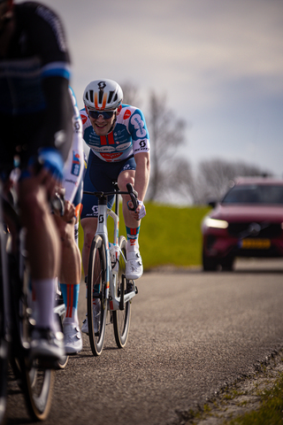 A man wearing a blue and white shirt riding his bike with the number 23 written on it.