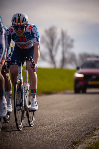 A cyclist wearing a blue and white uniform is on a road.