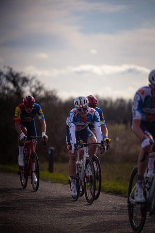 Three cyclists racing in a race sponsored by Wielrennen.