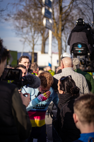 People gathered in a group watching bicycle racers pass by.