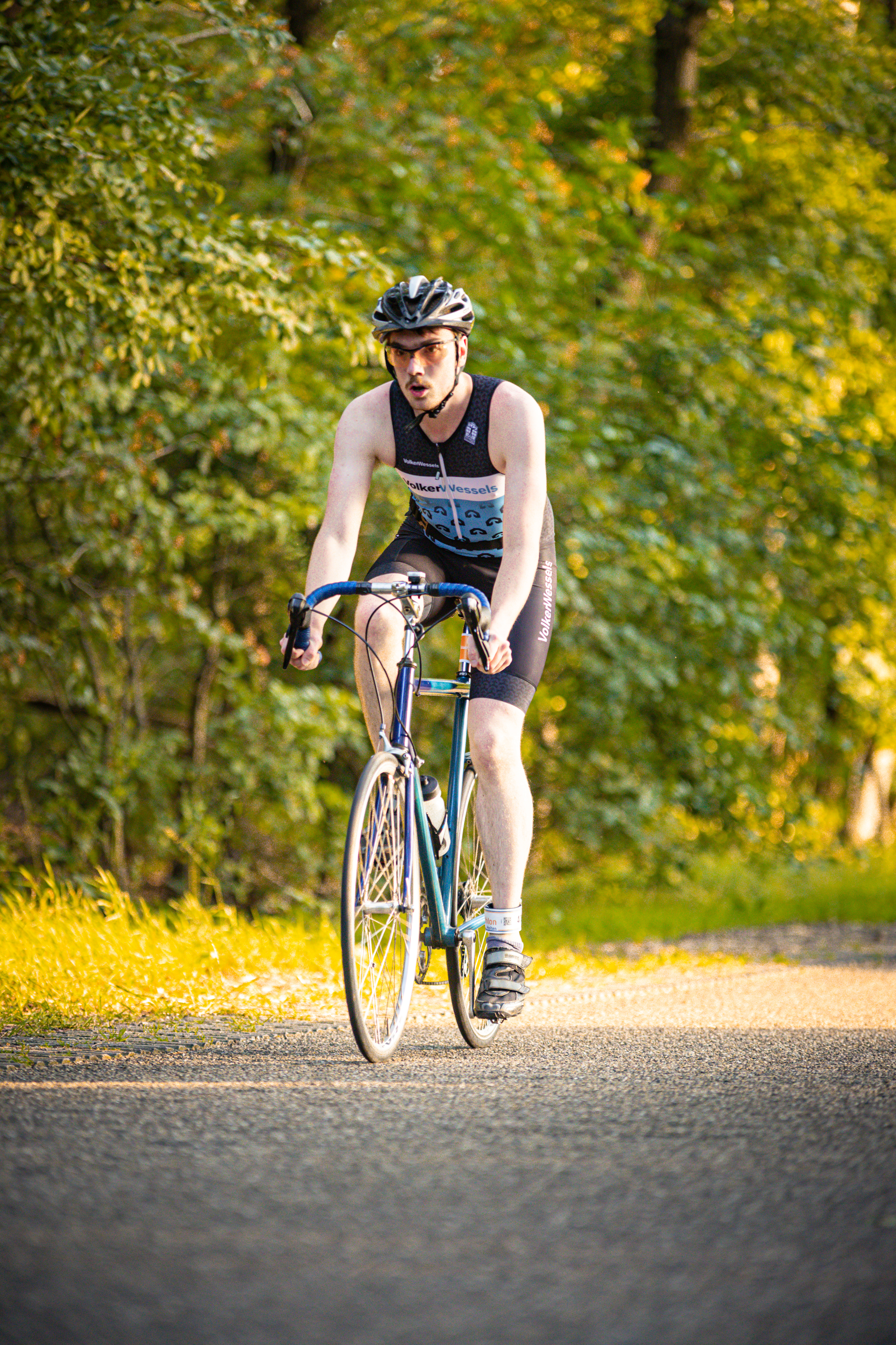 A man riding a blue bicycle wearing a black shirt and shorts.