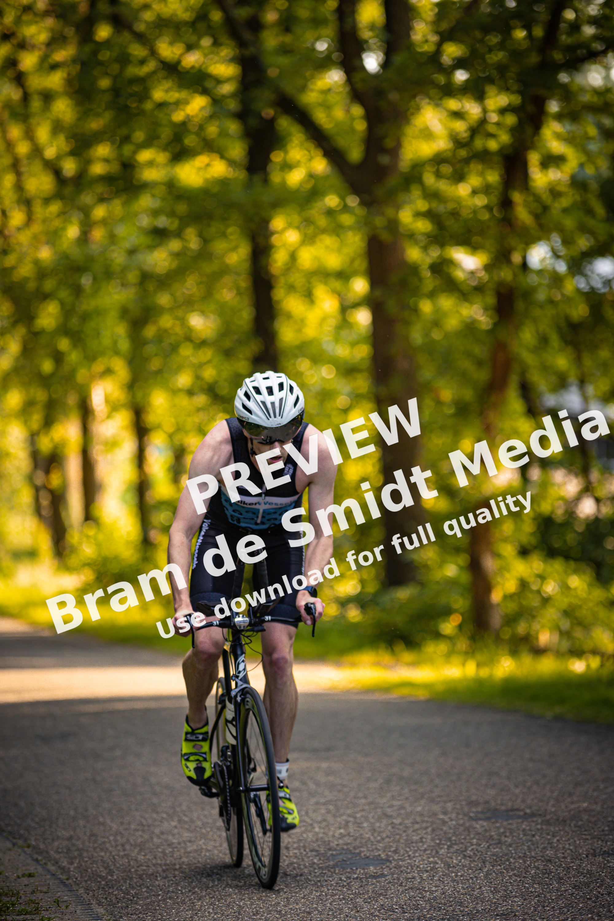 A man is riding a bike on the road while wearing an orange shirt with black and white stripes.