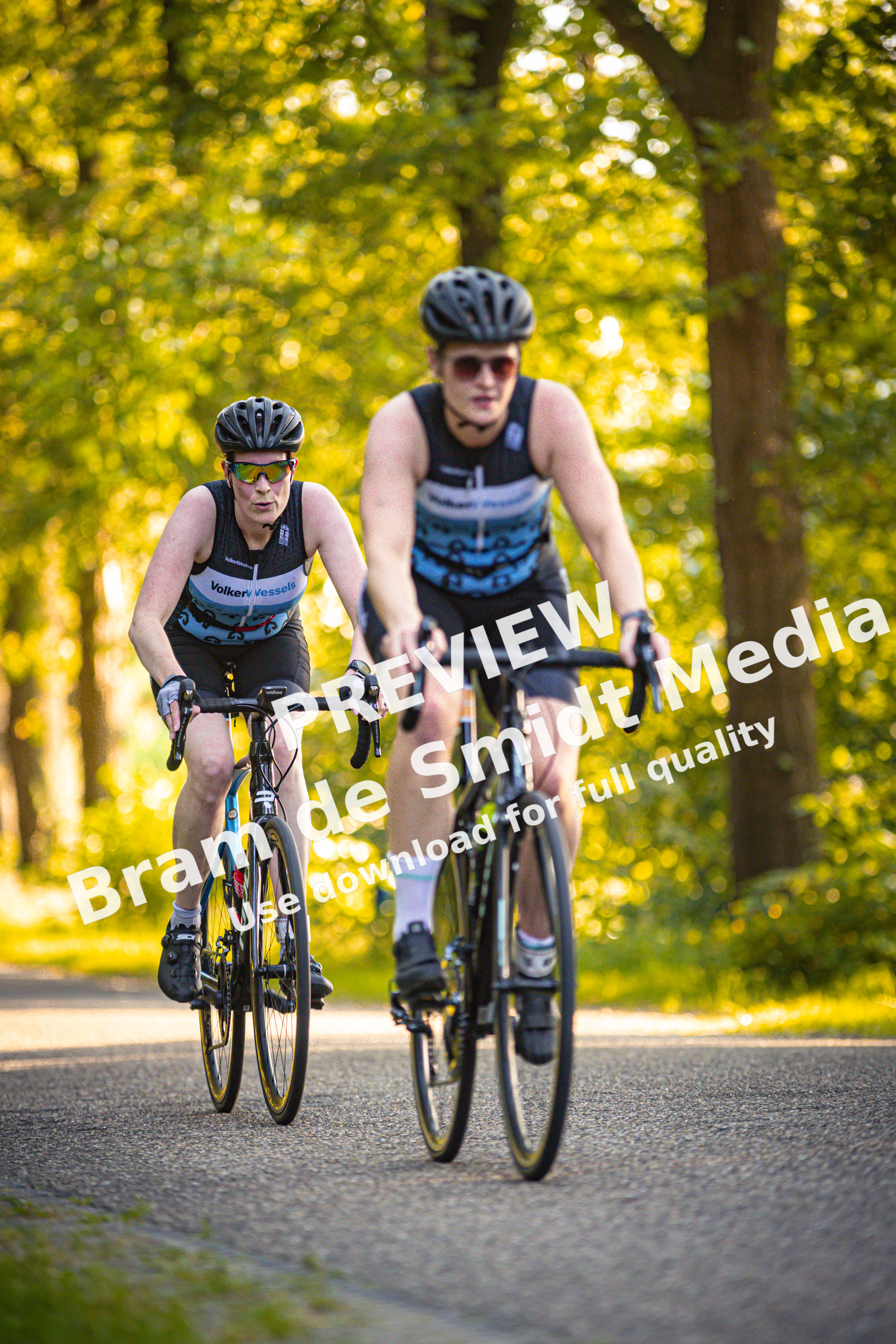Two cyclists riding their bikes on a road, one of which has the name Holten written on his shirt.