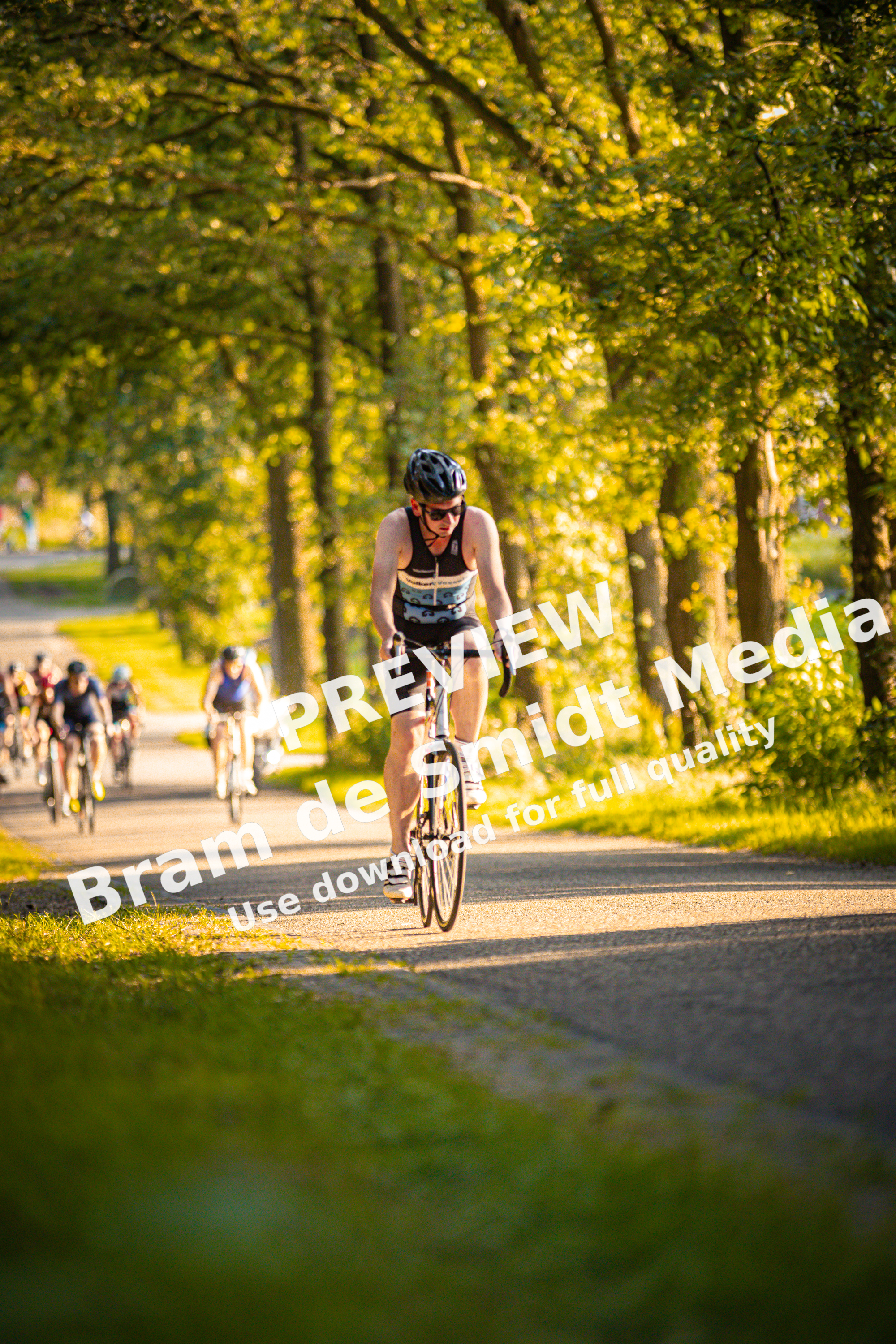 A woman wearing a black helmet is riding a bicycle down a road.