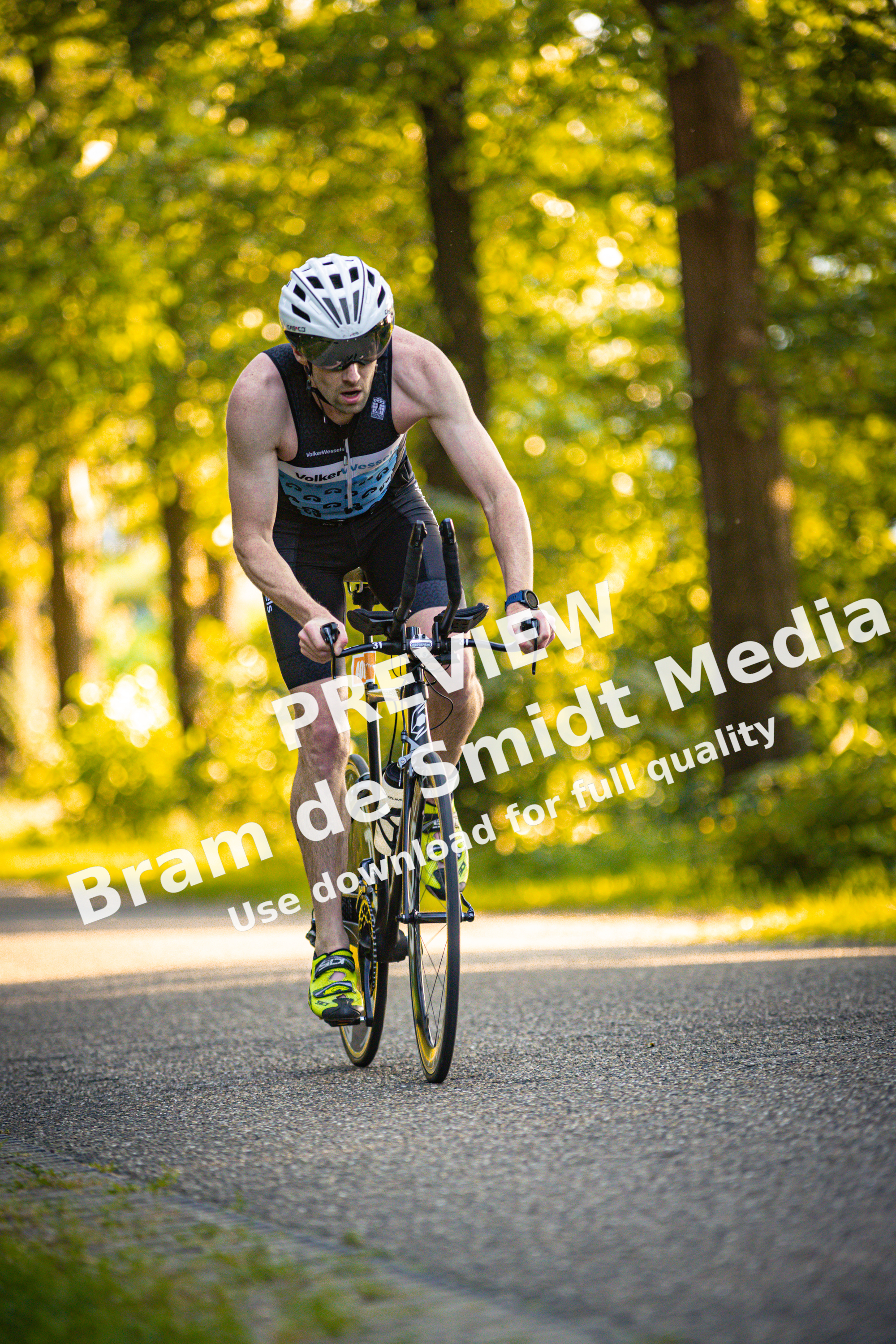 a man riding a bicycle down the road, wearing a triathlon outfit.