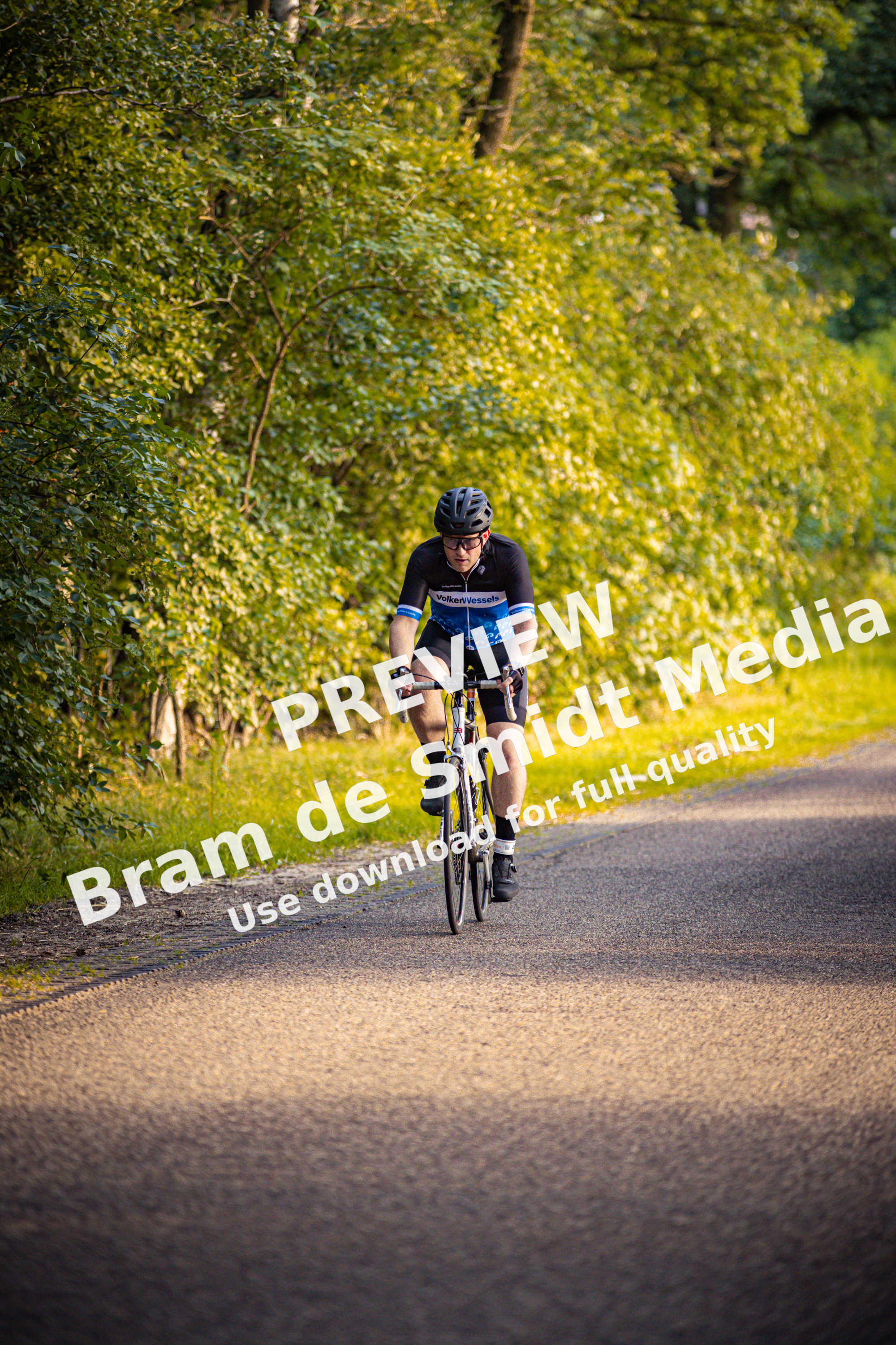A man on a bike is wearing a blue shirt that says triathlon.