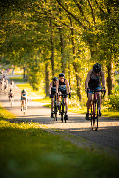 A group of cyclists on a road with one cyclist wearing a bib that says "Kaiser".