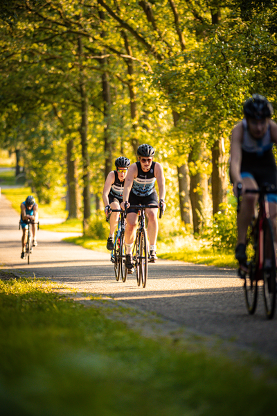 Three people are riding their bikes on a road during the day.