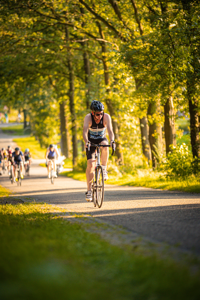 A woman wearing a black helmet is riding a bicycle down a road.