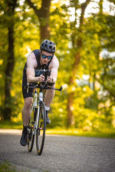 A man on a bicycle, wearing a black shirt and helmet.