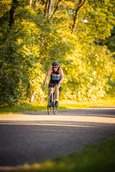 A woman is riding a bike down the road in a yellow forest.