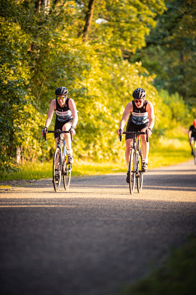 Two cyclists riding on a road with one wearing the number 44.