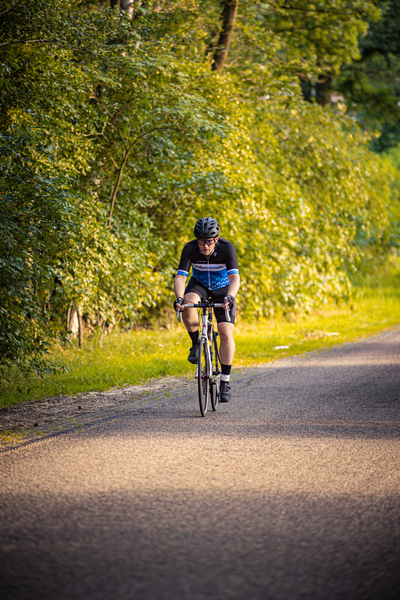 A man on a bike is wearing a blue shirt that says triathlon.