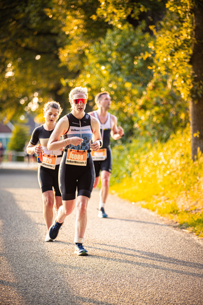 A woman running in a marathon with the number 1000 on her shirt. She's leading three other runners.