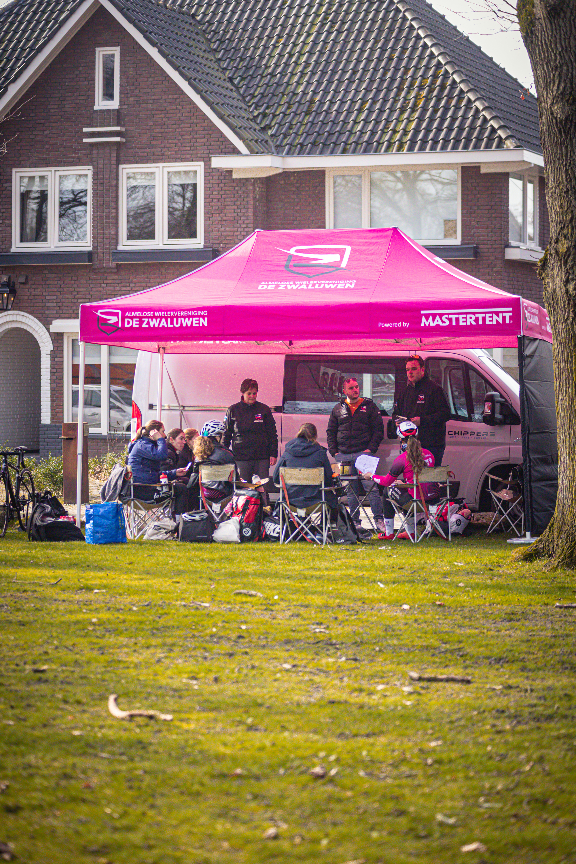 A tent with a logo on it and some people sitting under it.