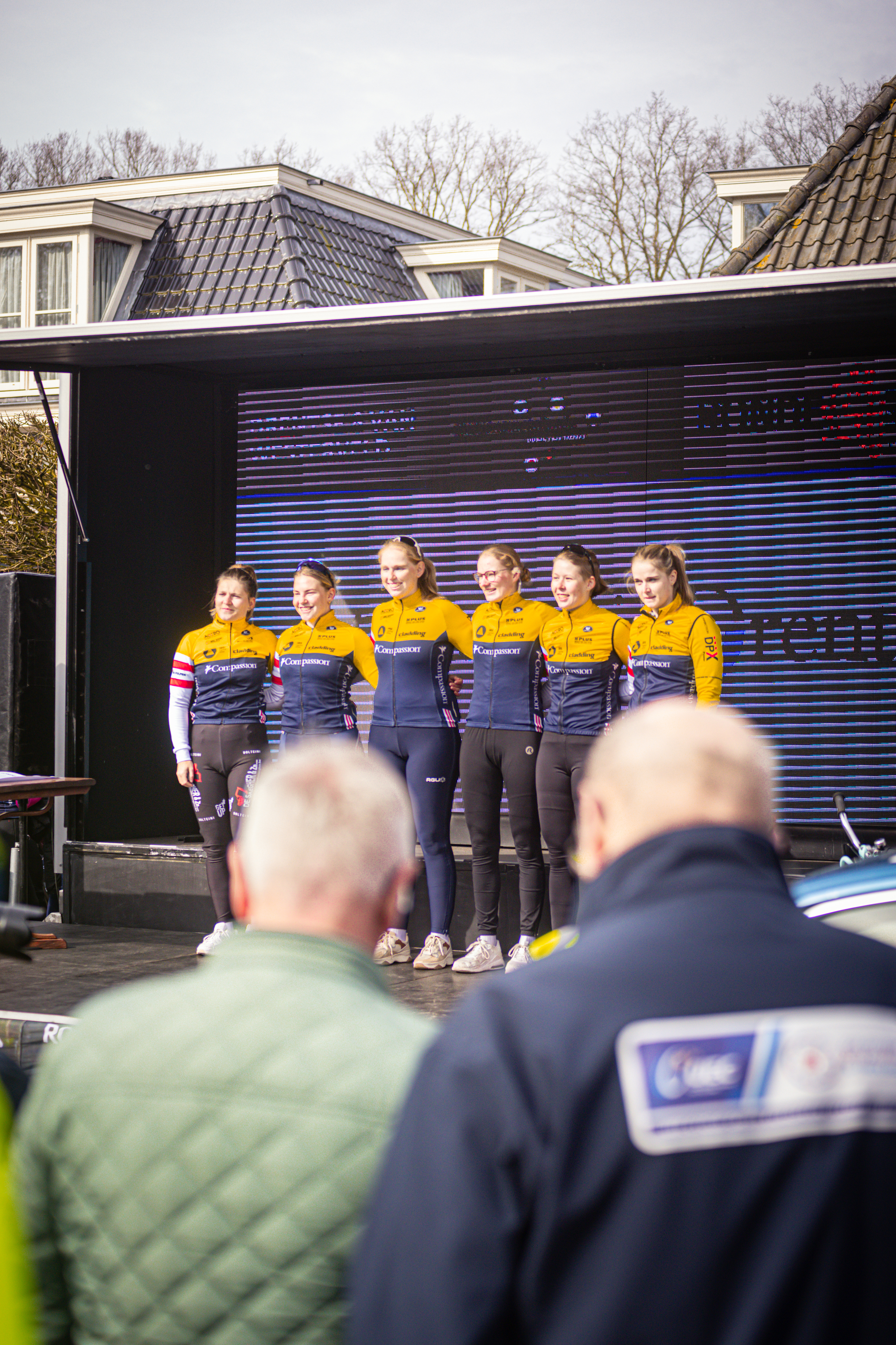 Eight women wearing matching uniforms pose on a stage.