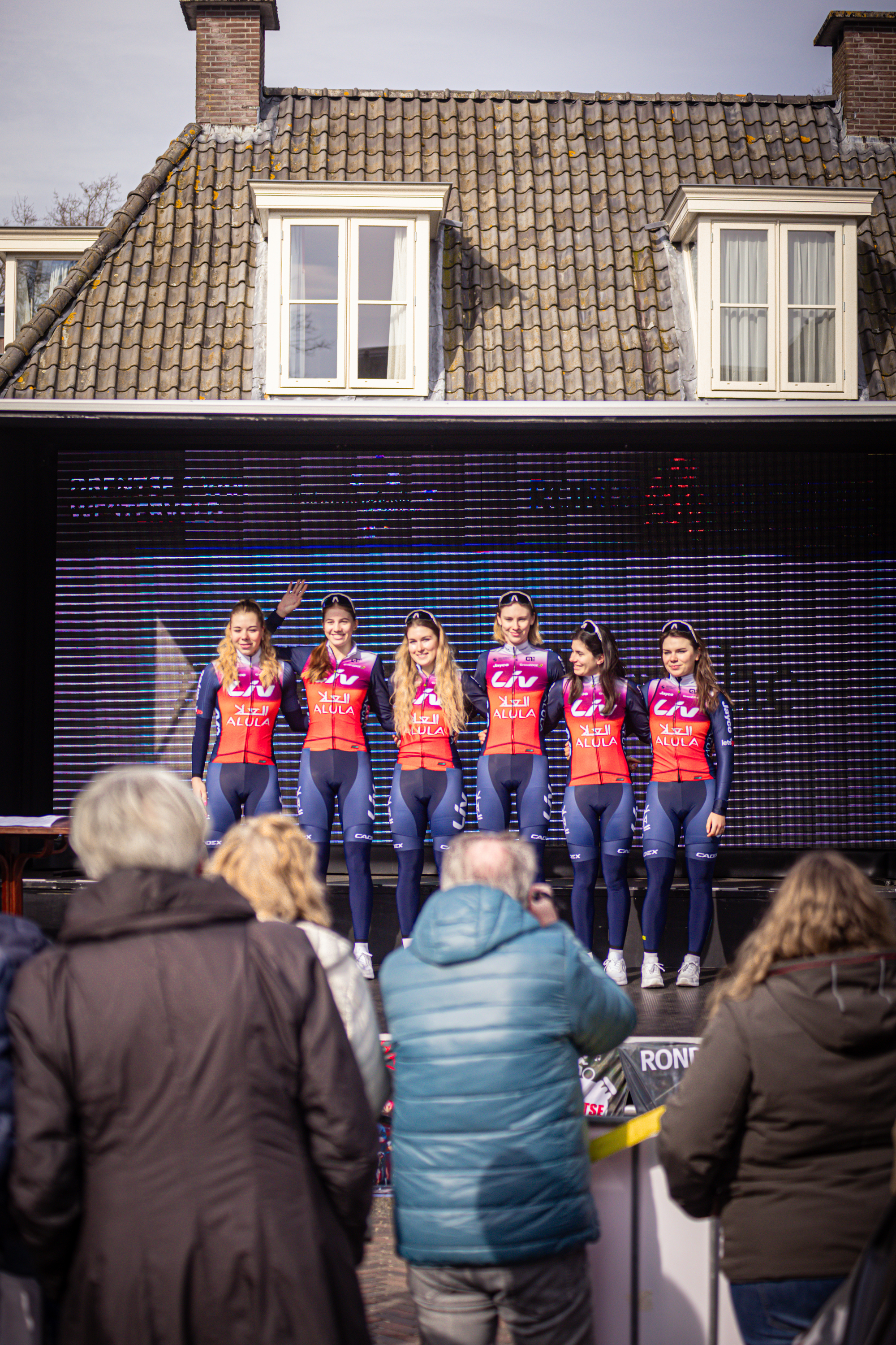 A group of women in red, white and blue jerseys stand on stage at a sporting event.