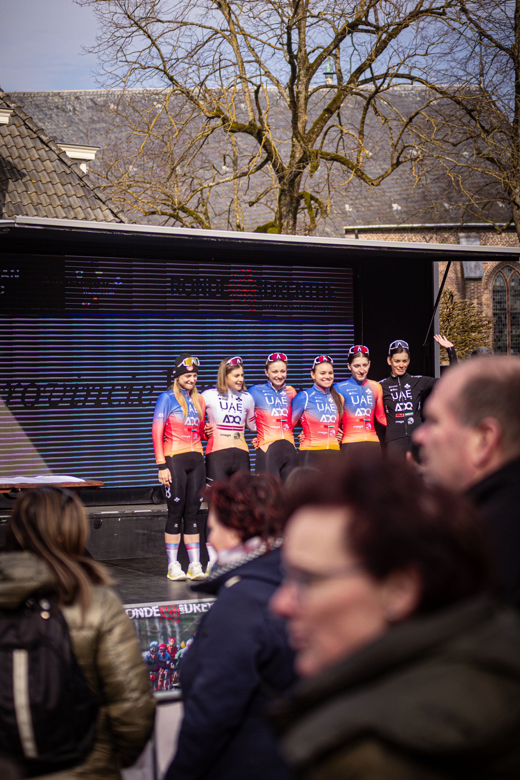 A group of people posing together, the woman in front is wearing a red and white top with the word "Drentse" on it.