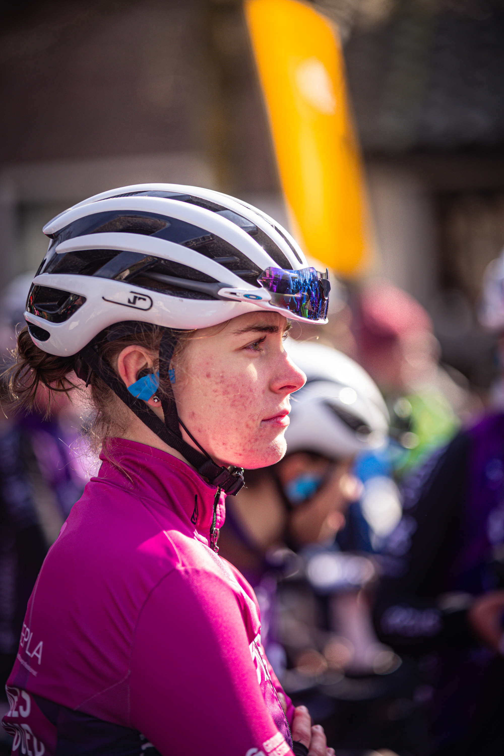 A young girl is wearing a pink jersey and a white helmet while looking to the right.