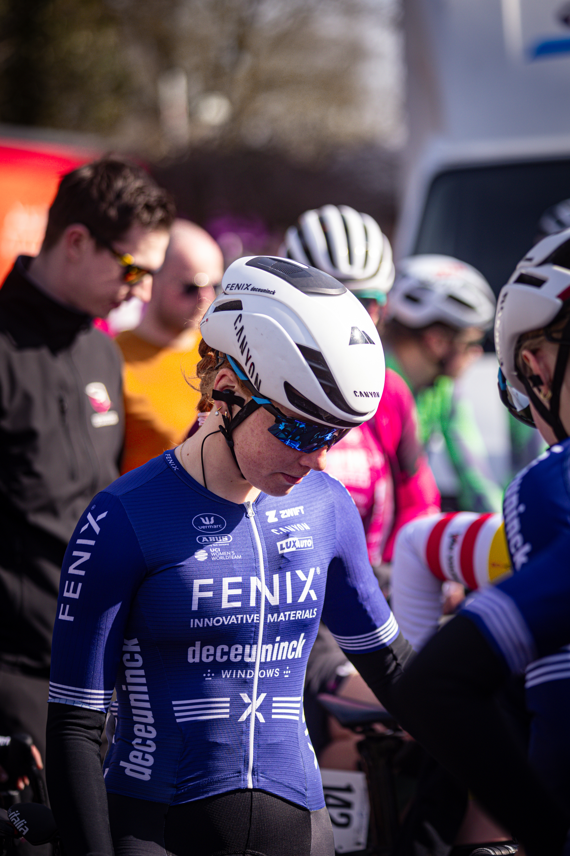 Two cyclists standing next to each other wearing helmets.