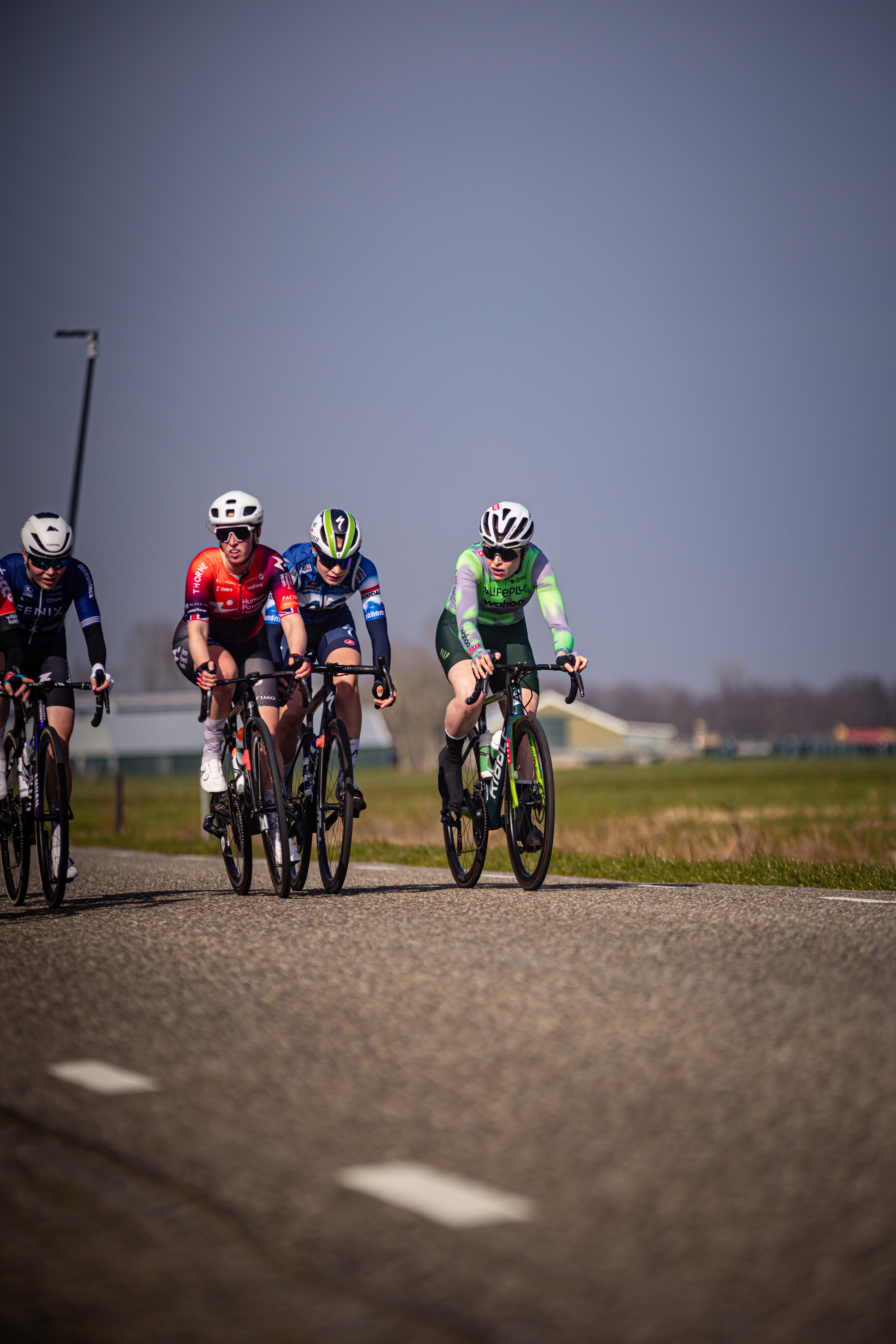 Five cyclists are wearing helmets and riding bikes down a street.