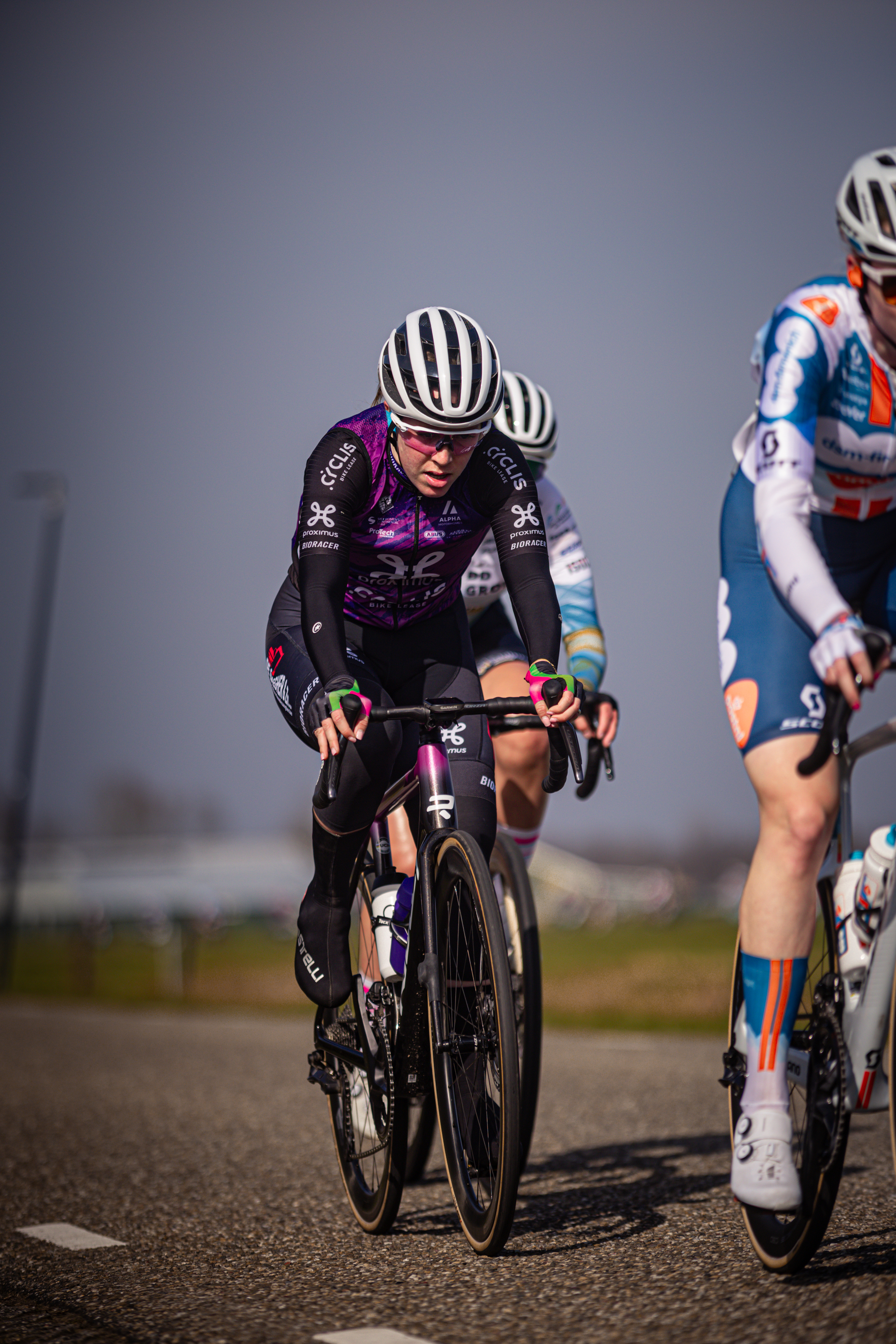 Three cyclists are riding side by side on a road with the number 8.