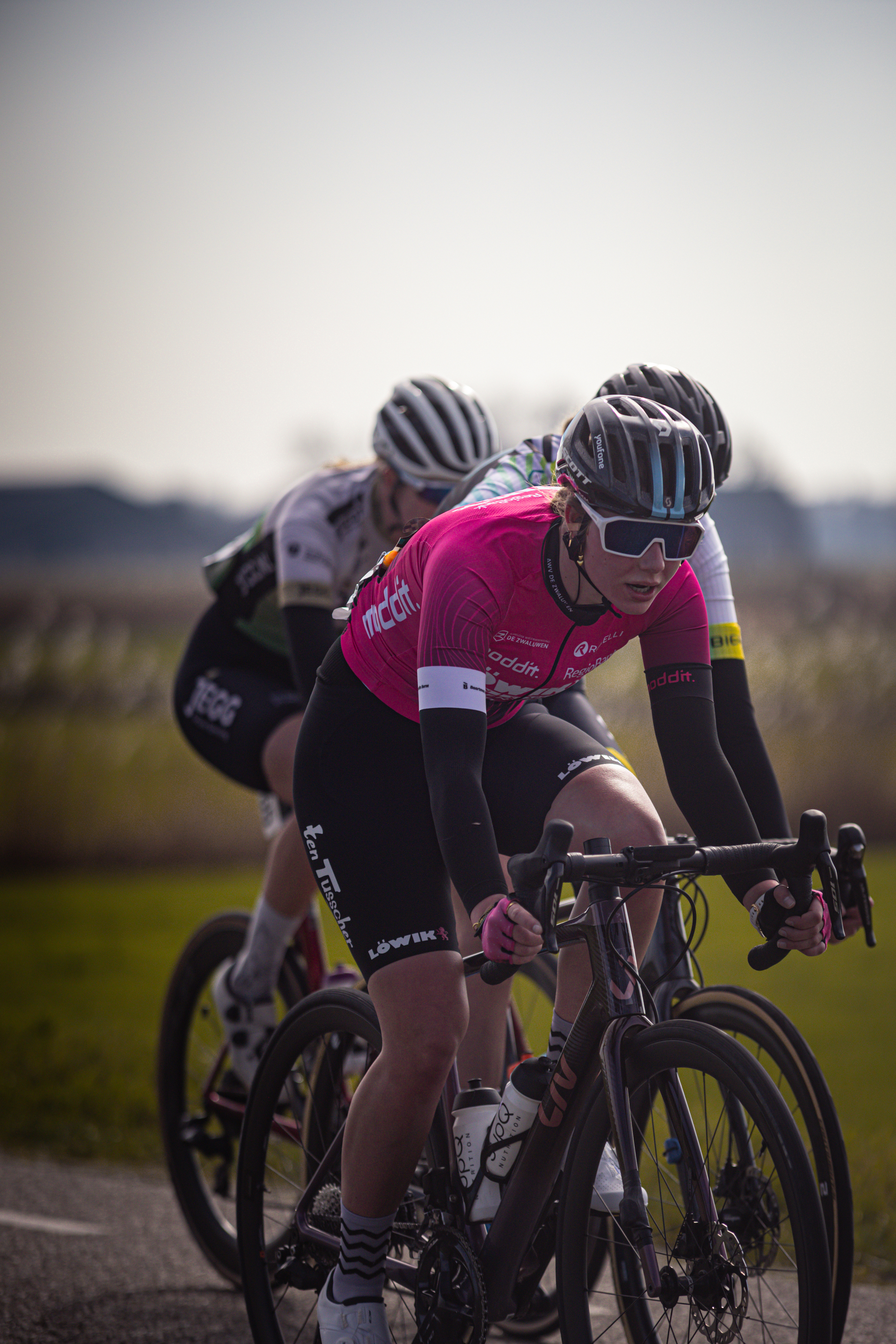 Two cyclists racing on a road with one wearing black and the other in pink.