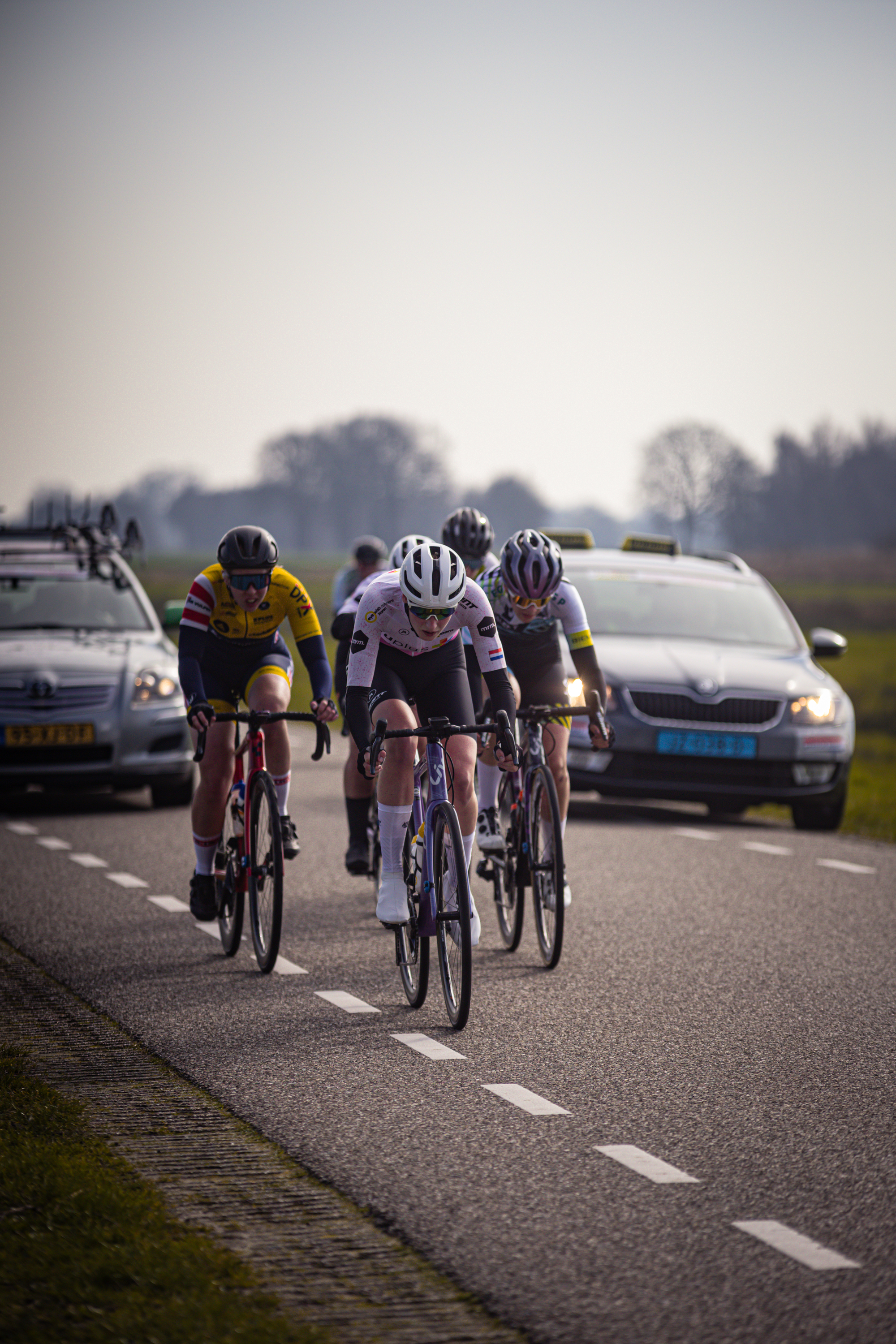 A group of cyclists race down a road on what looks like a sunny day.