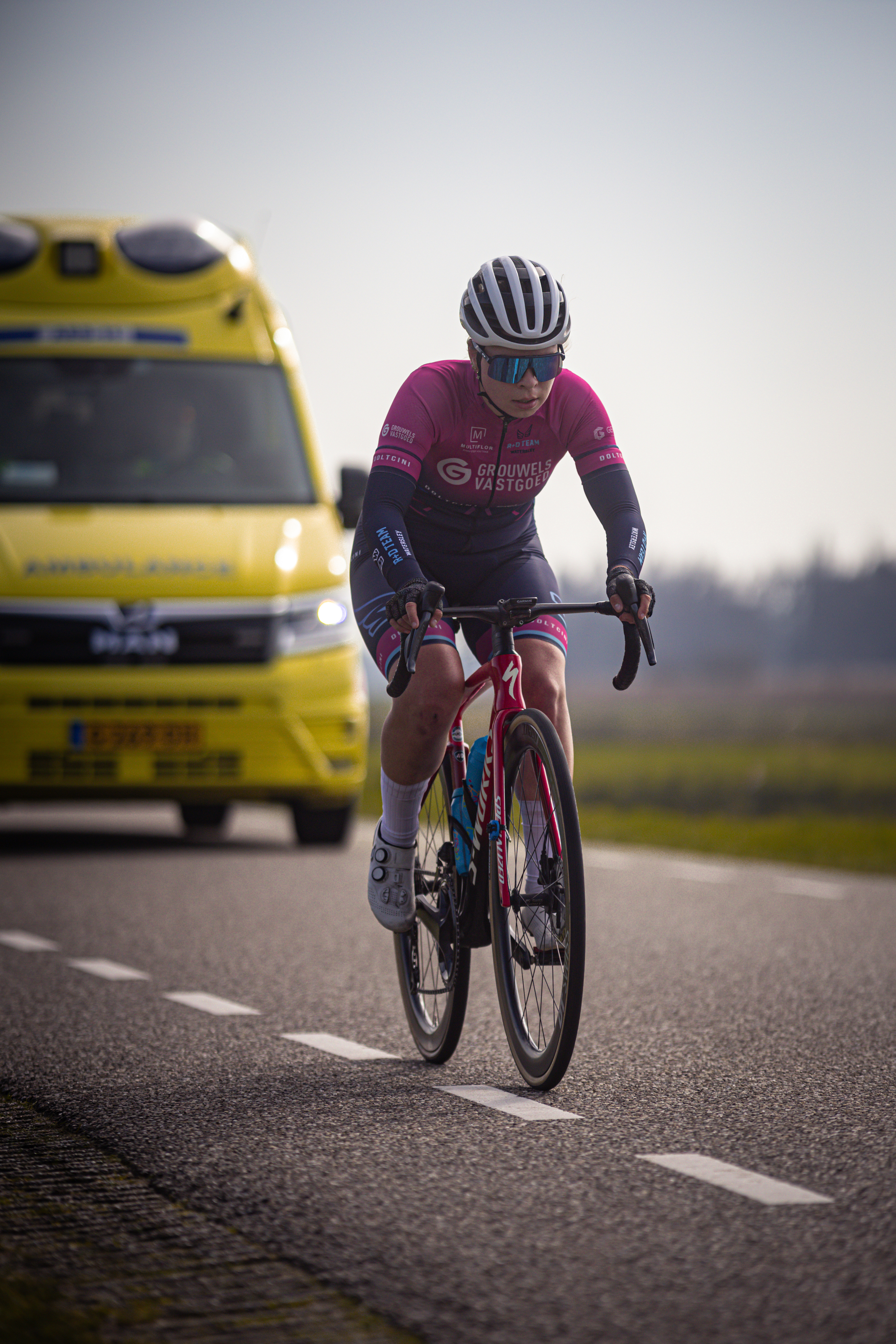 A woman in a pink jersey rides her bicycle on the road.