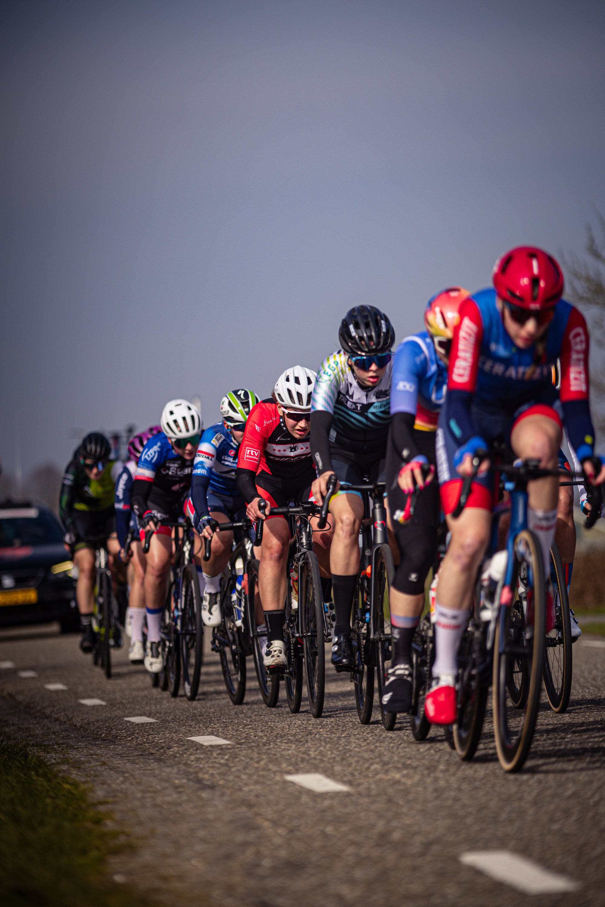 The image shows a group of cyclists riding on a road in the Netherlands.