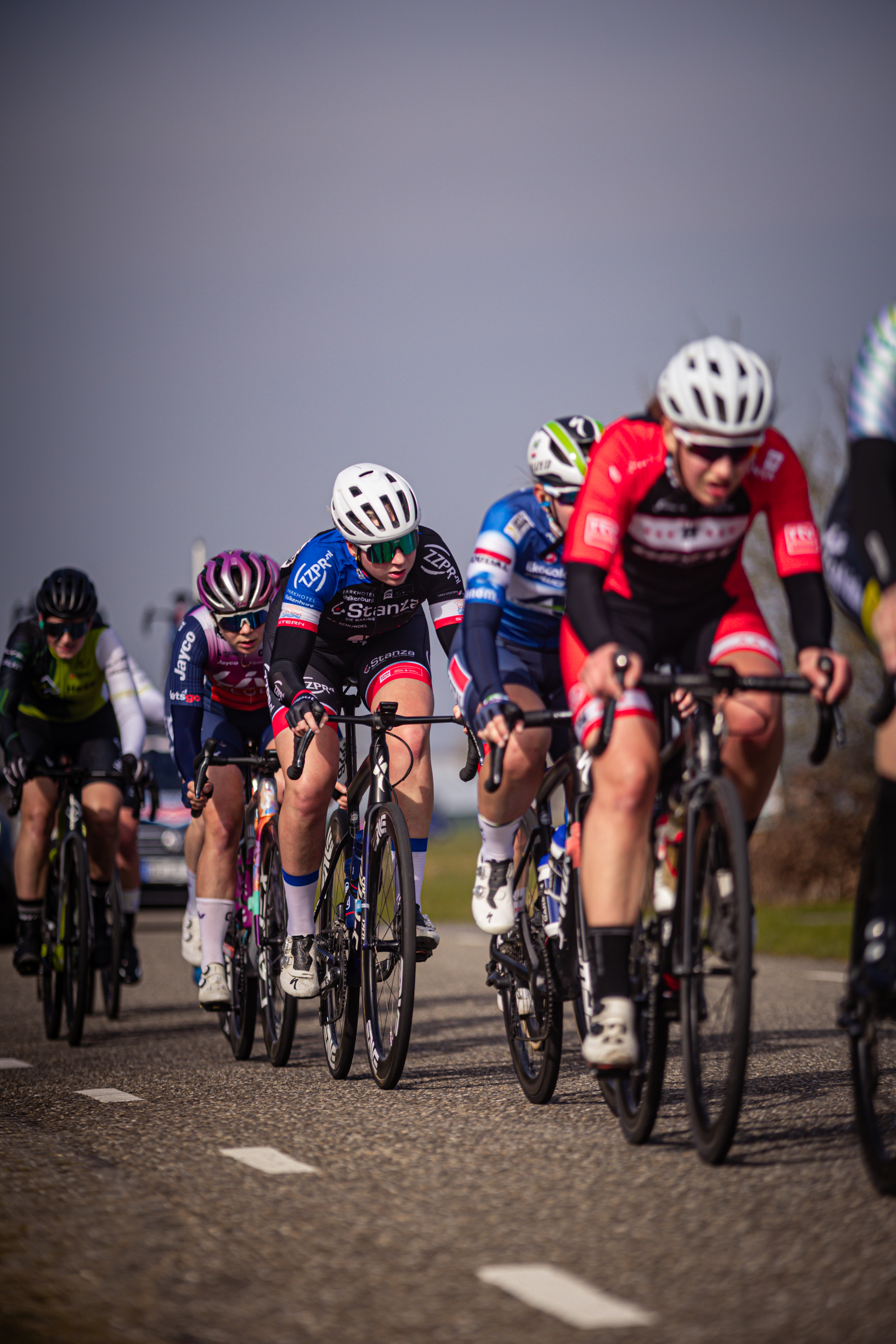 A group of cyclists race down a road in the Netherlands.