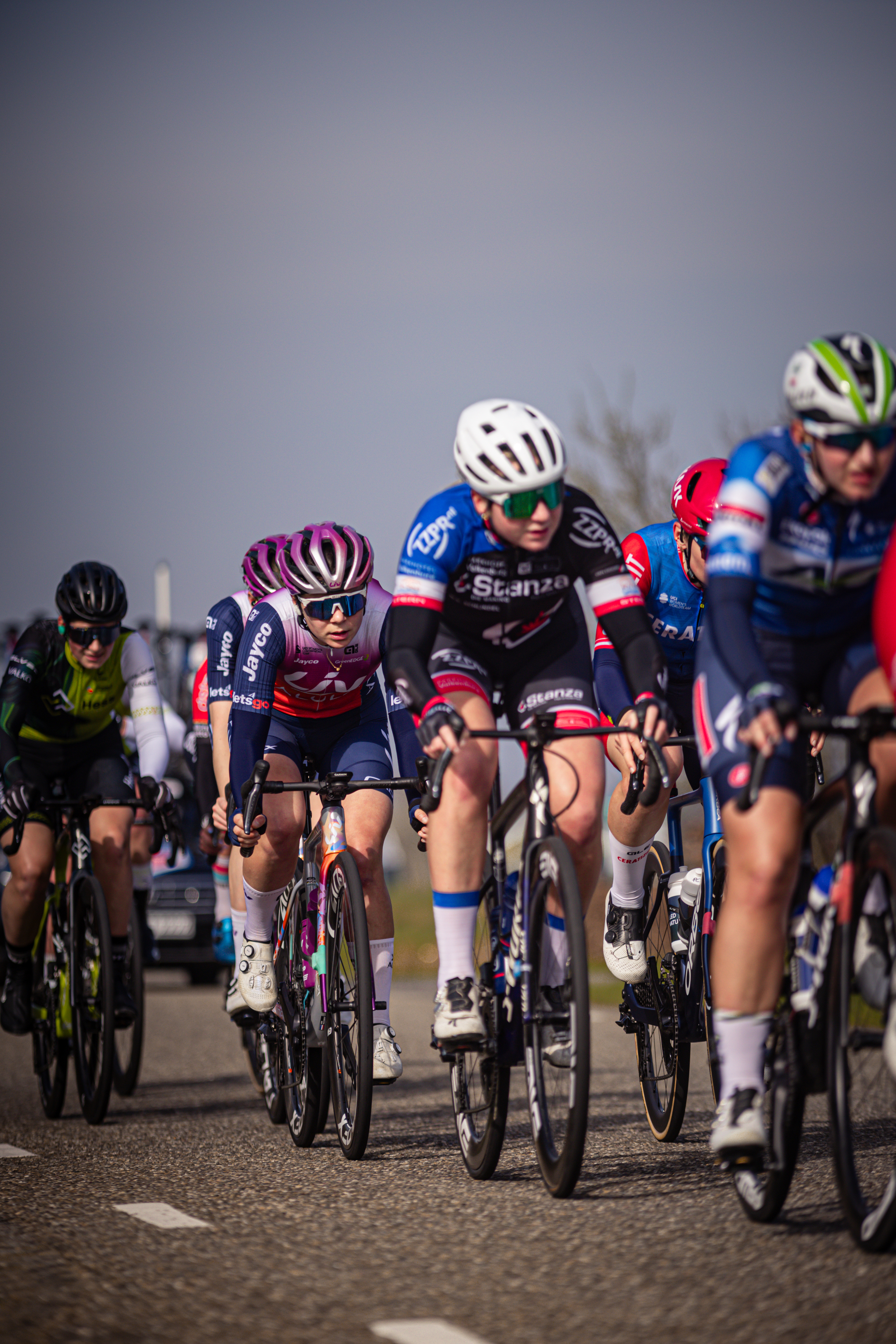 Six cyclists on a track with one of them wearing a blue jersey with the word "Bouwke" on it.