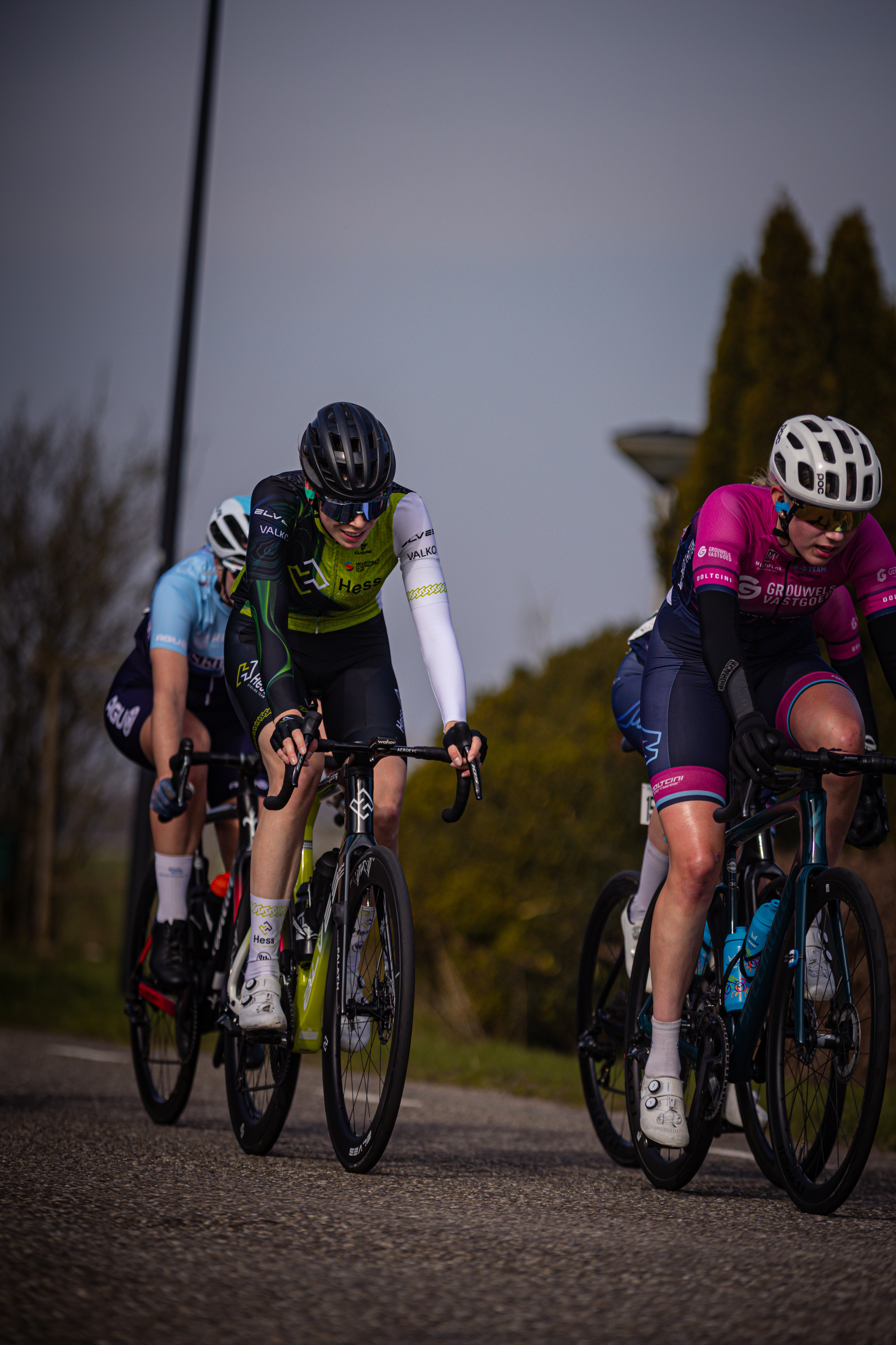 Three cyclists on a street with one wearing a helmet and another wearing sunglasses.