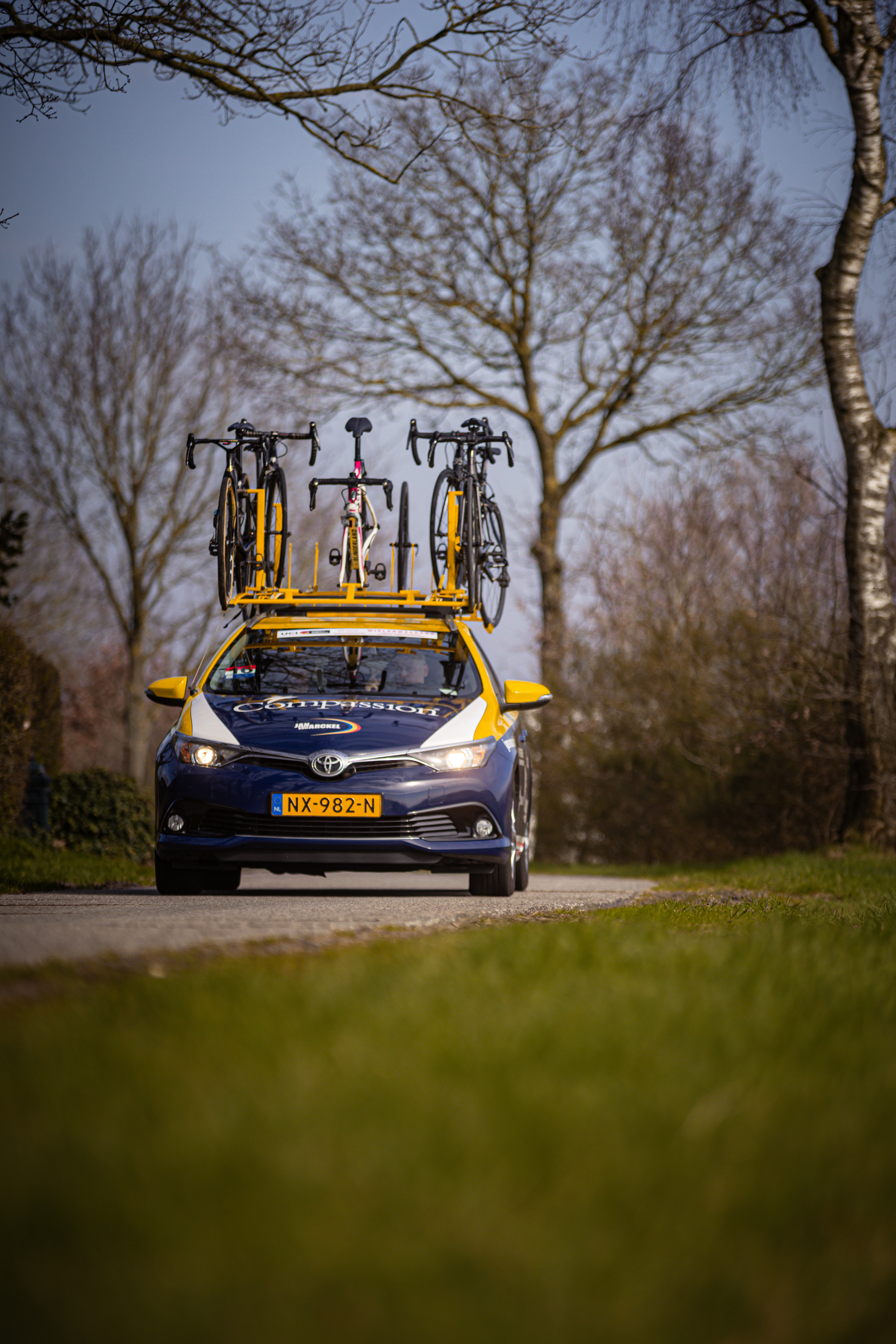 A blue car is filled with bicycles, and the license plate says 2024.