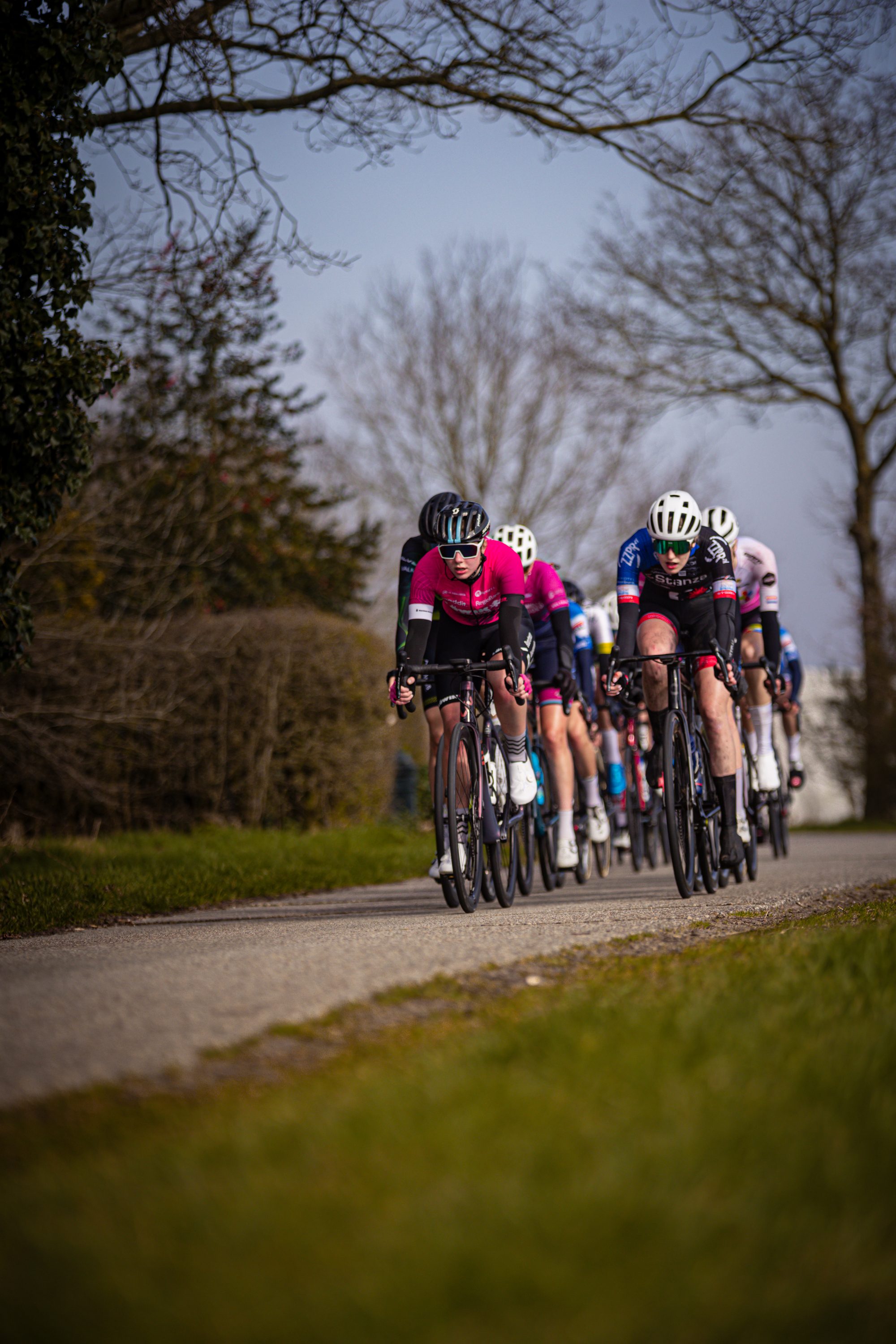 Three cyclists in a race are wearing helmets with the letters "W" on them.