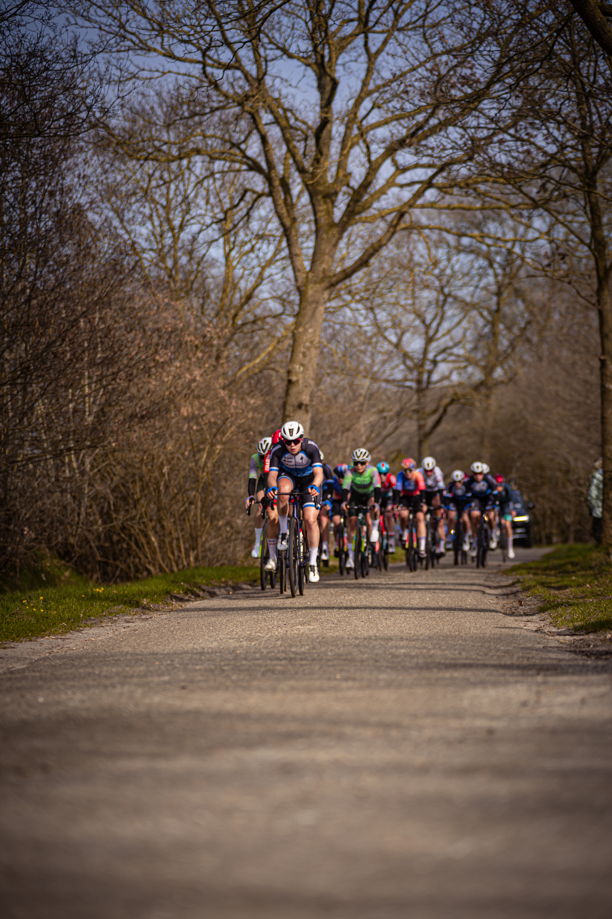 A group of cyclists racing down a dirt road in the countryside on Drentse 8 van Westerveld.