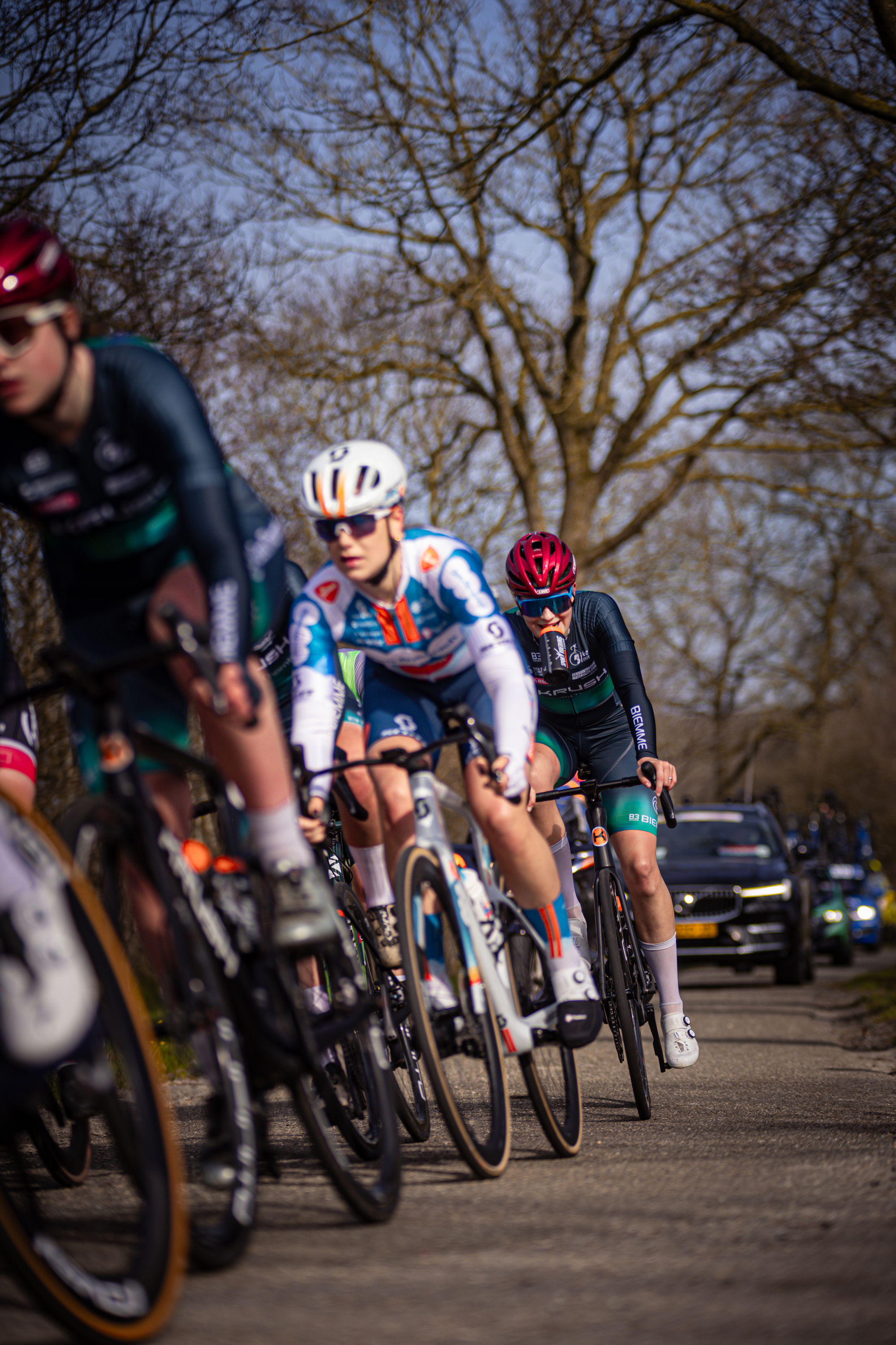 Three cyclists are on a road and one of them is wearing number 15.