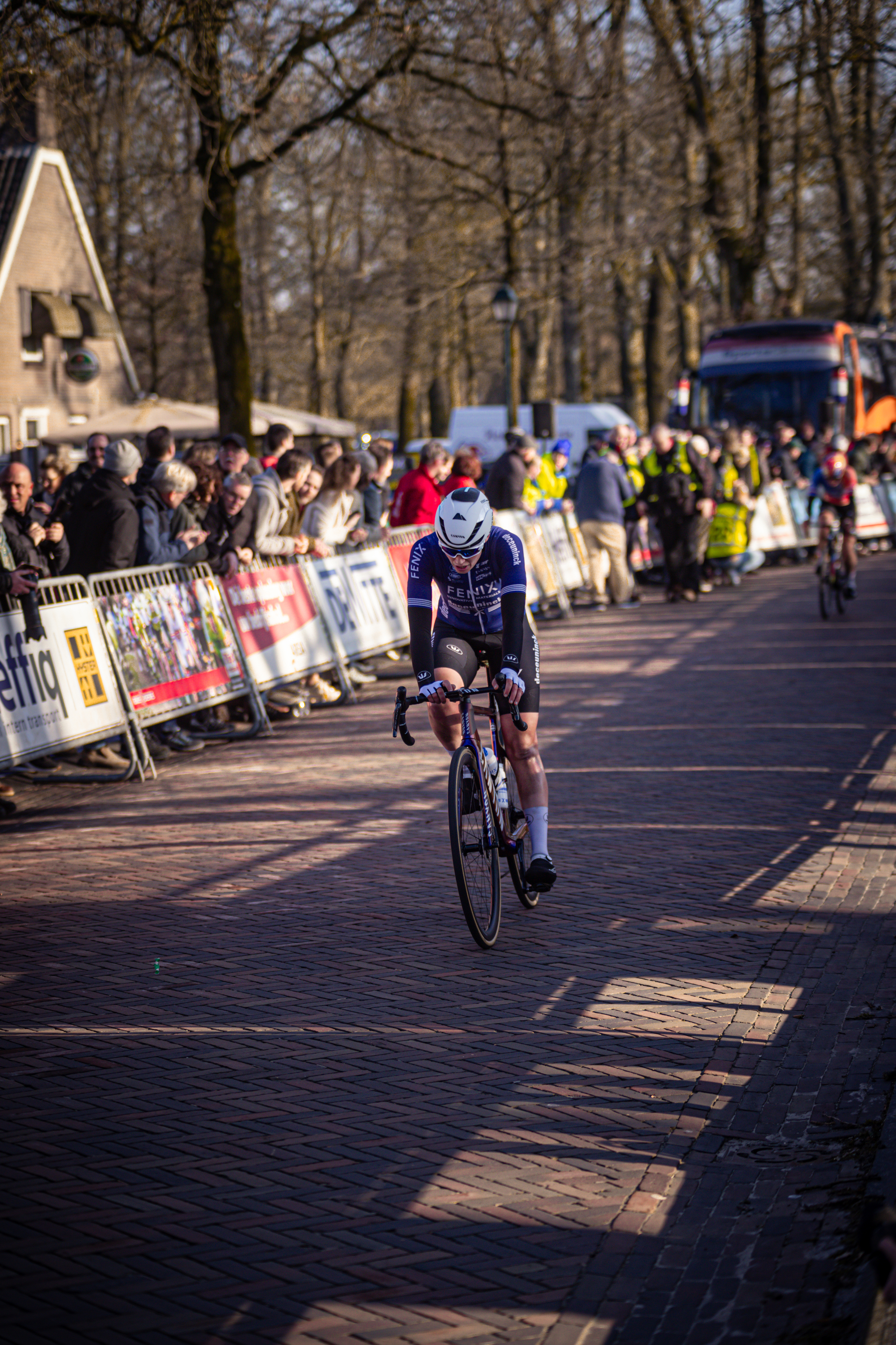 A cyclist is riding down a street in the Netherlands during a competition.