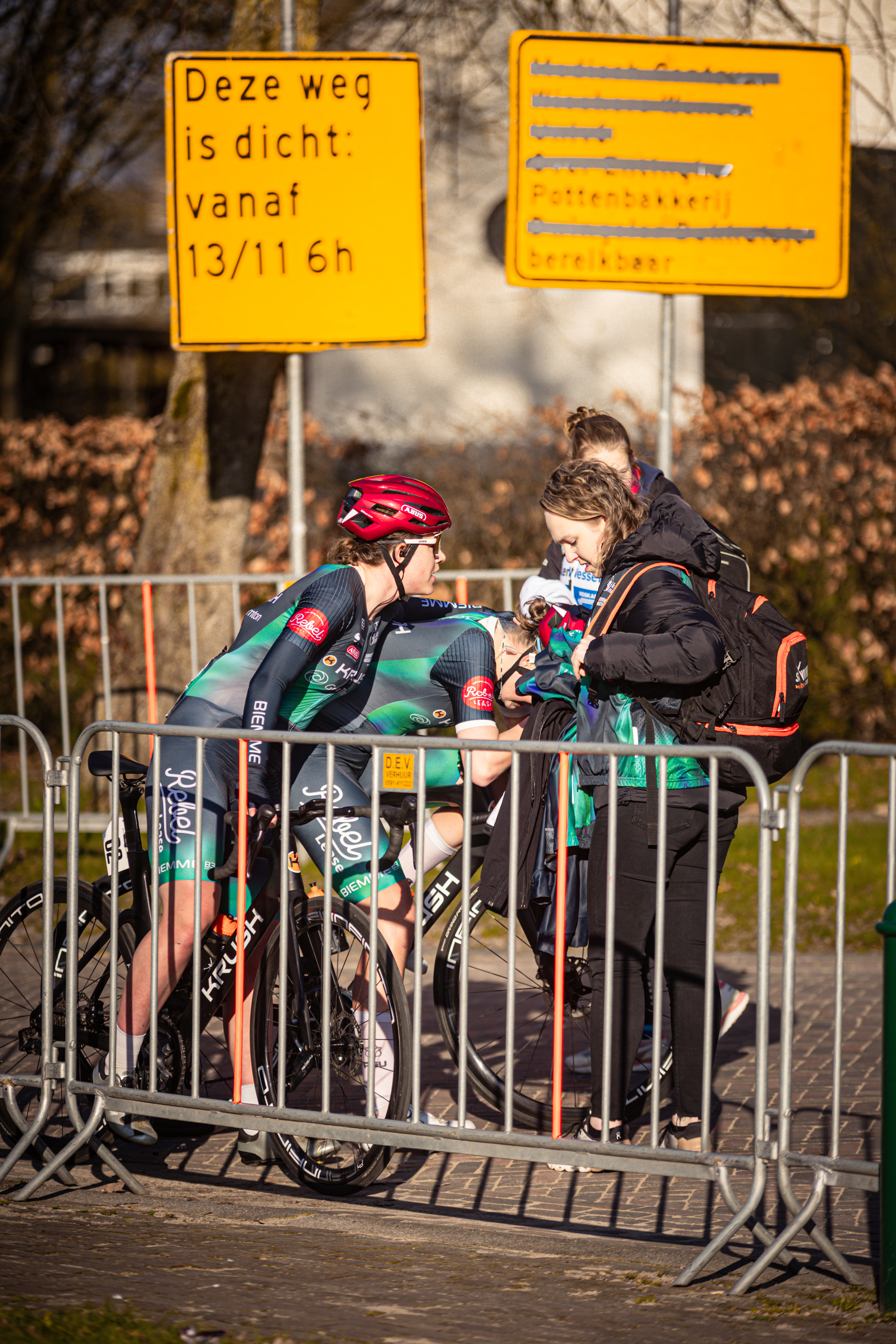 A group of people are standing behind a fence at the Drentse 8 van Westerveld event.