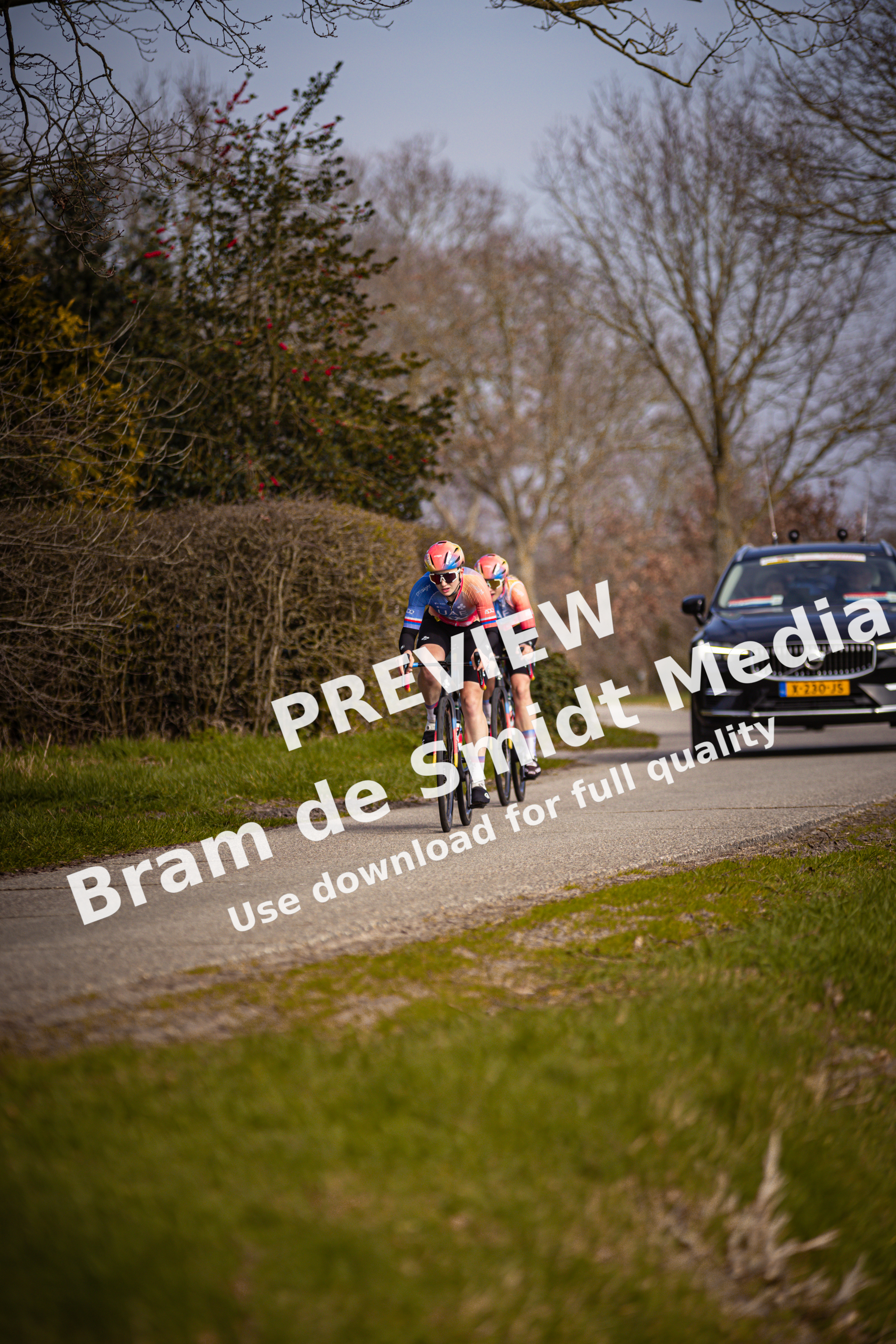 Two cyclists are racing on the road, they are wearing numbers 5 and 7.