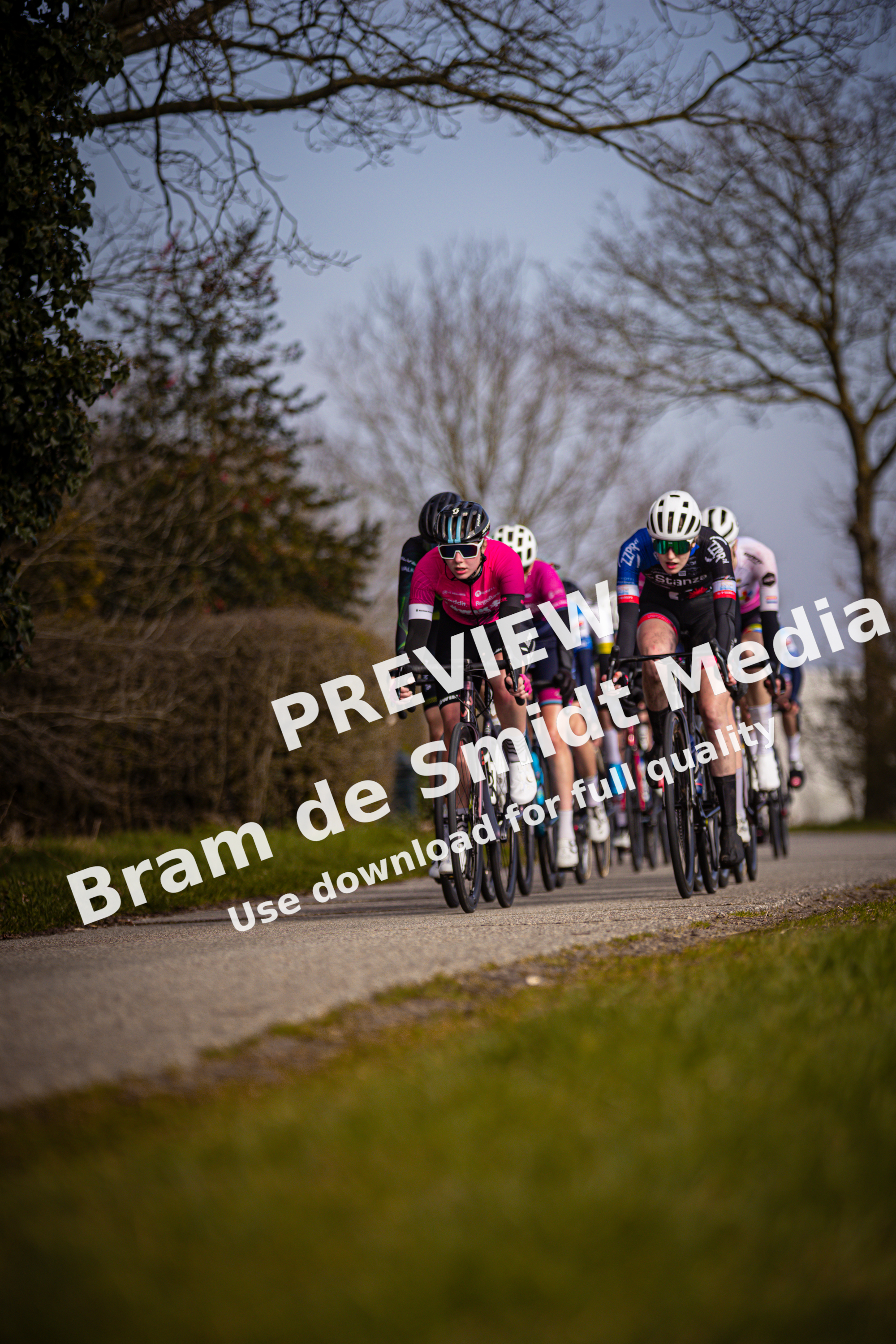 Three cyclists in a race are wearing helmets with the letters "W" on them.