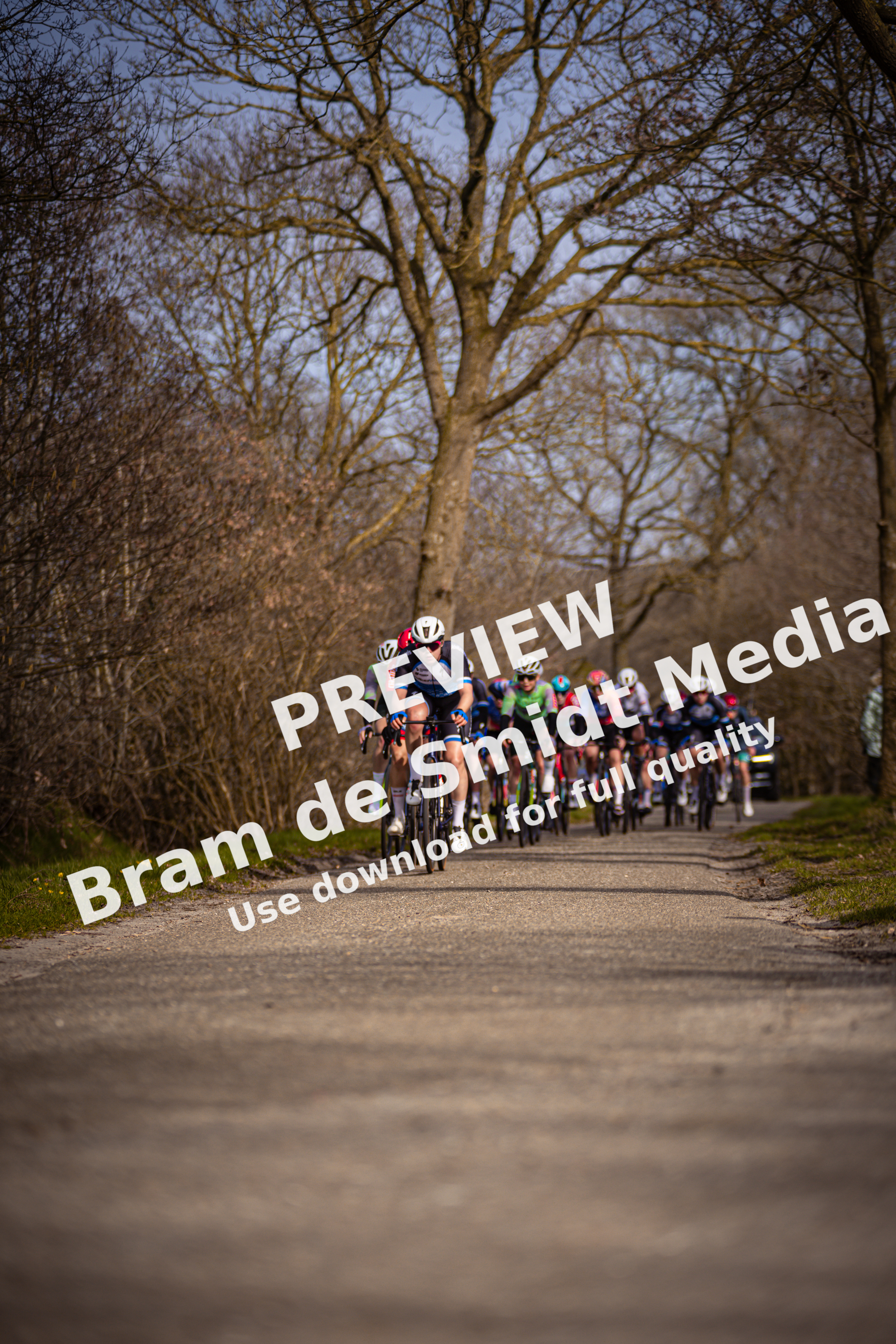 A group of cyclists racing down a dirt road in the countryside on Drentse 8 van Westerveld.