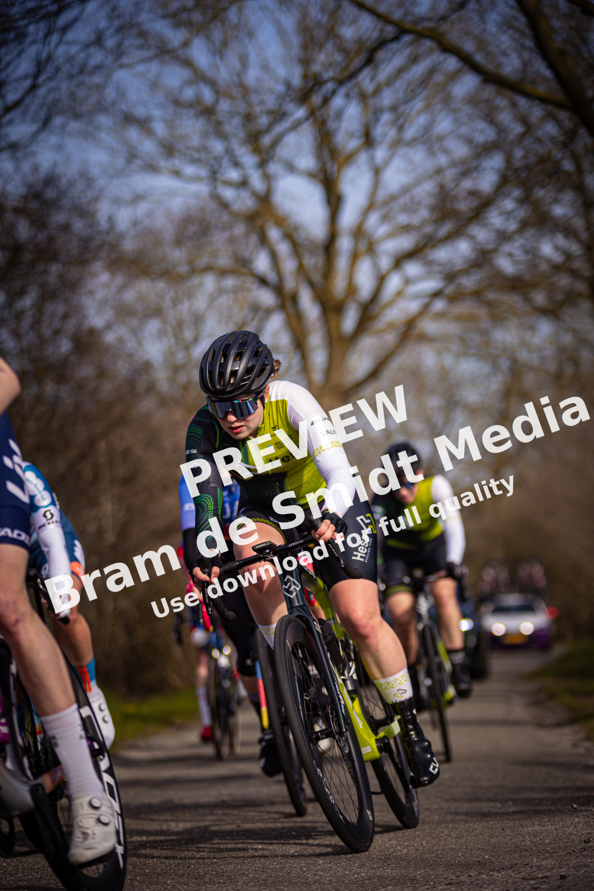 a group of cyclists race on a road with one in the foreground.